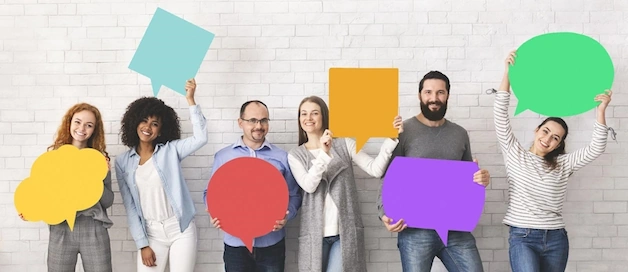 Group of happy diverse people holding empty colourful speech bubbles and smiling at camera